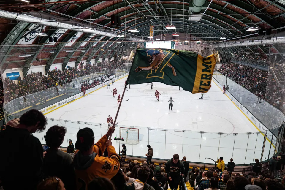UVM hockey fans cheer as a Vermont flag waves over the ice.